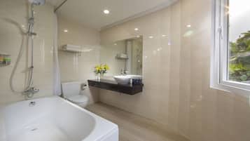 A modern bathroom with a bathtub, toilet, and shower.