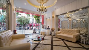 A hotel lobby with a chandelier, a reception desk, a sofa, and a coffee table.