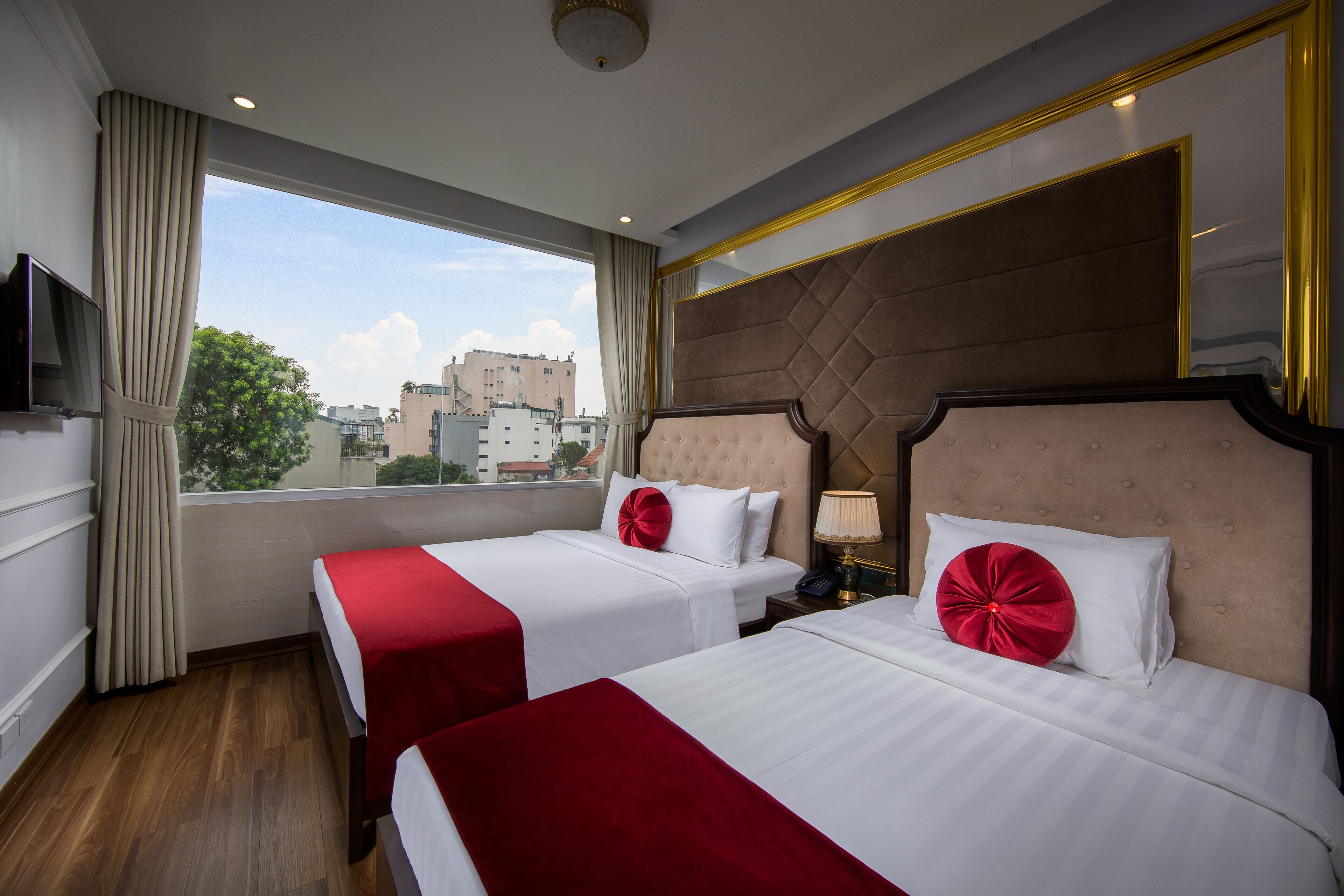 A hotel room with two beds, a large window, and a view of the city.