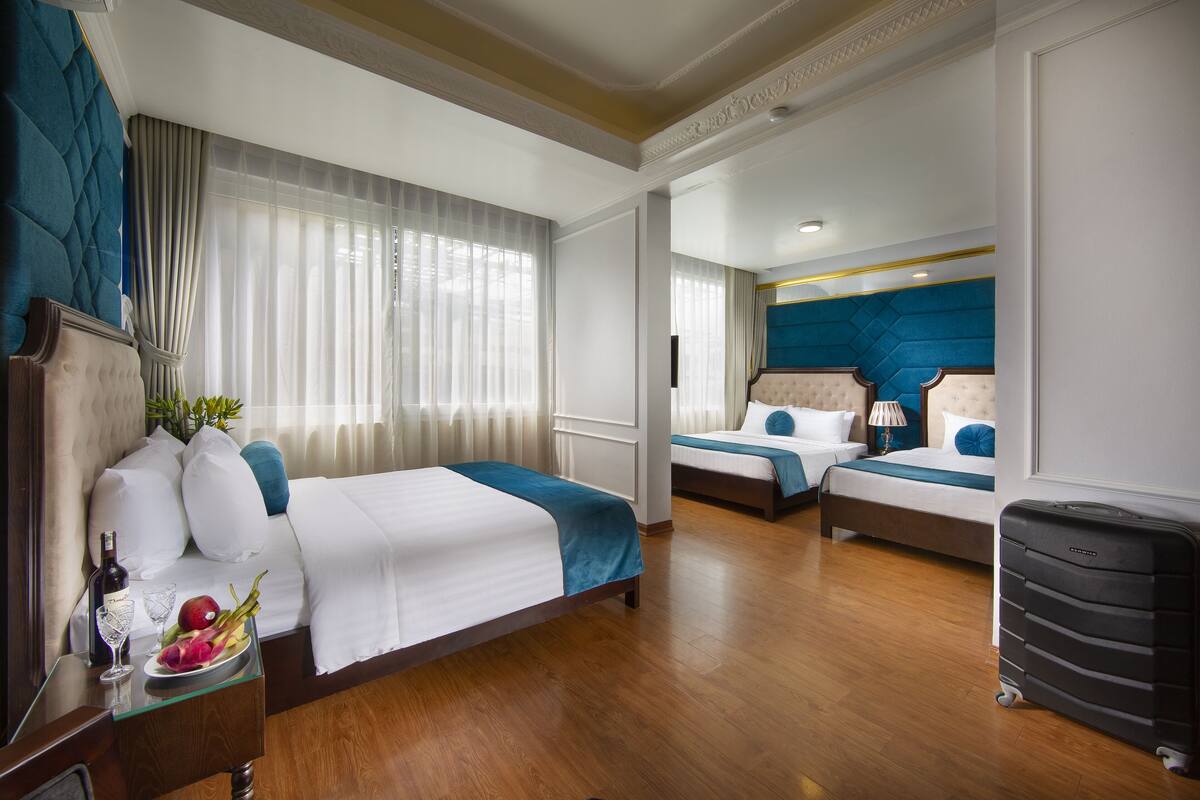 Habitació d'hotel amb dos llits, un terra de fusta, un minibar i una maleta.