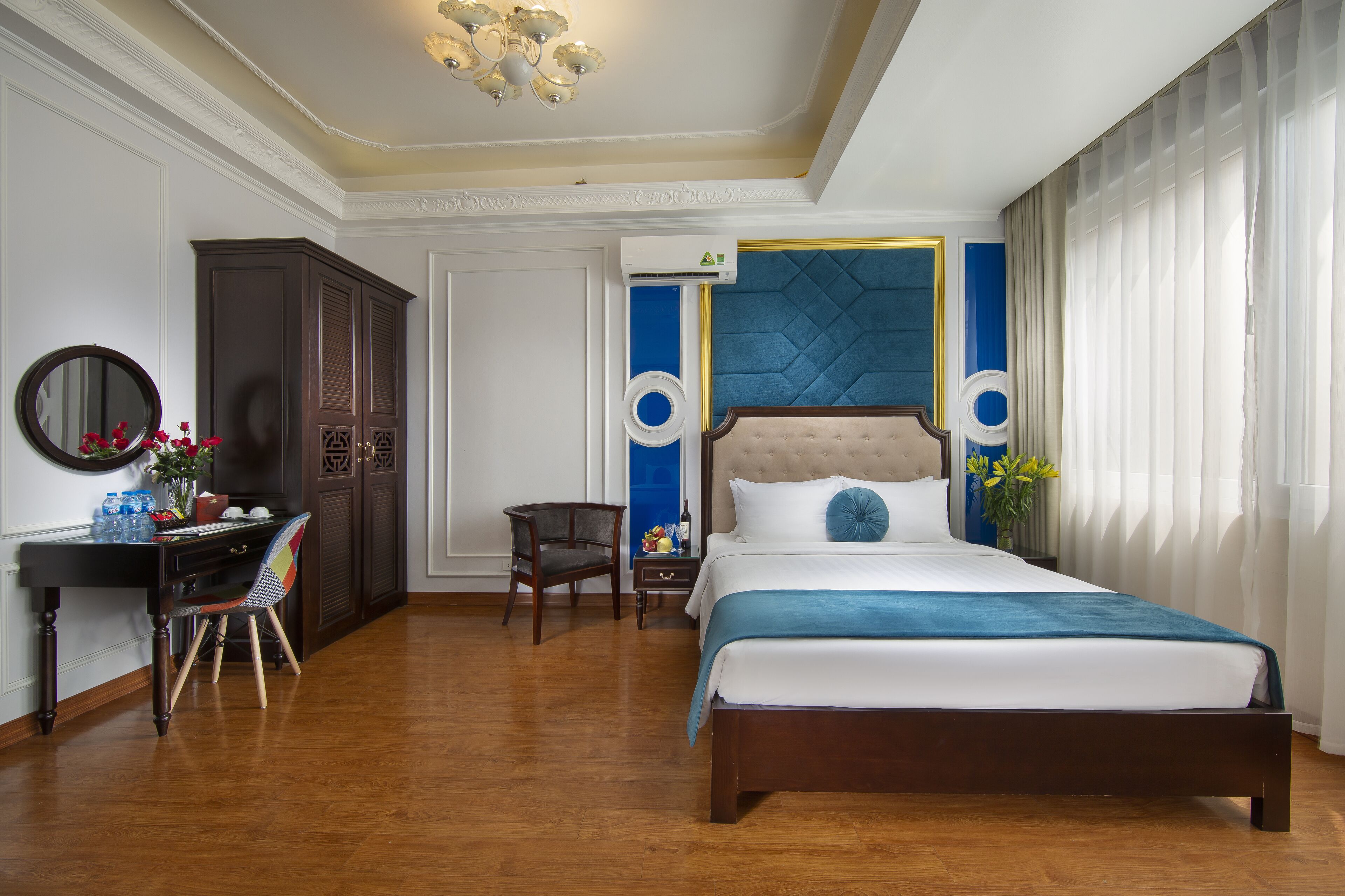 A bedroom with a large bed, a desk with a chair, a wardrobe, and a mirror.
