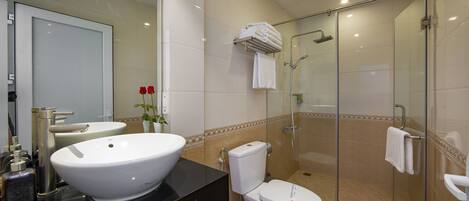 A modern bathroom with a large white sink, a toilet, and a glass-enclosed shower area.