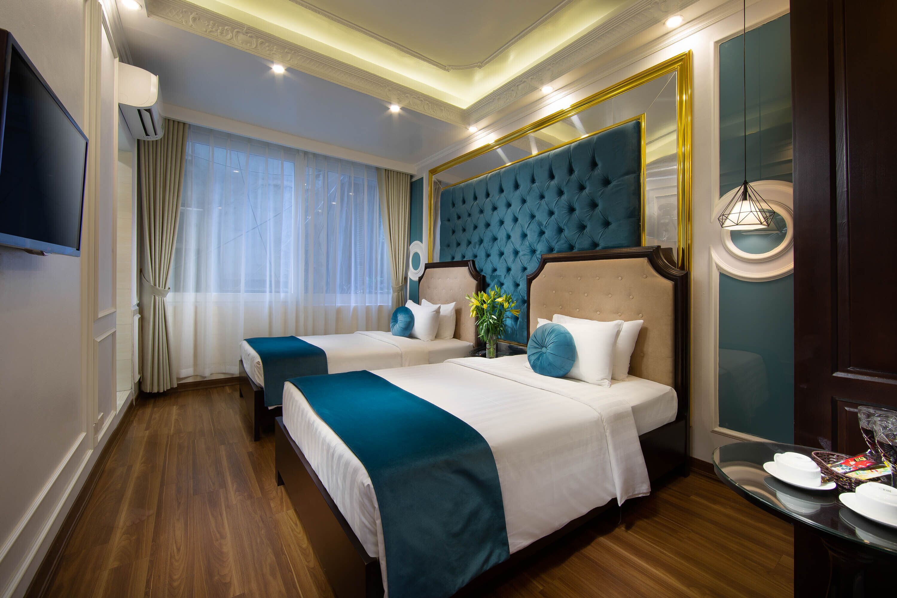 Een hotelkamer met twee bedden, een grote spiegel, een televisietoestel en een zithoek met een tafel en stoelen.