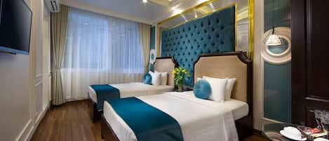 Een hotelkamer met twee bedden, een grote spiegel, een televisietoestel en een zithoek met een tafel en stoelen.
