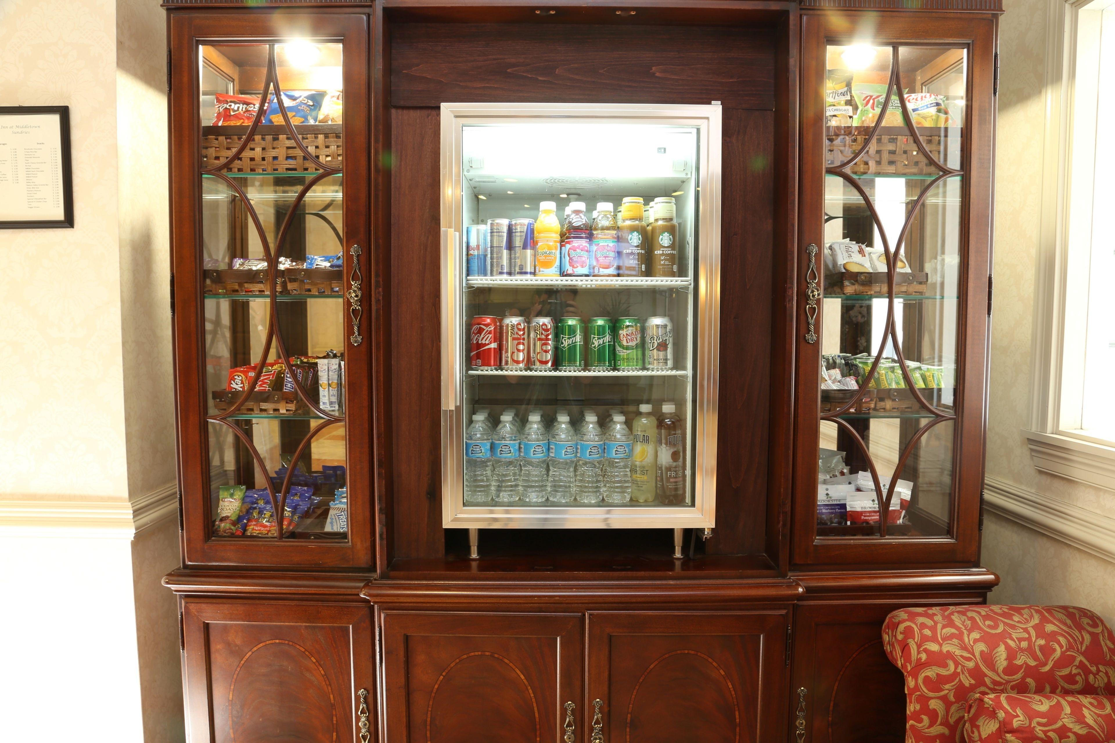 Un refrigerador para bebidas con varias estantes, rodeado de armarios de madera.