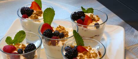 Four glasses of yogurt parfait with berries and granola on a white plate.