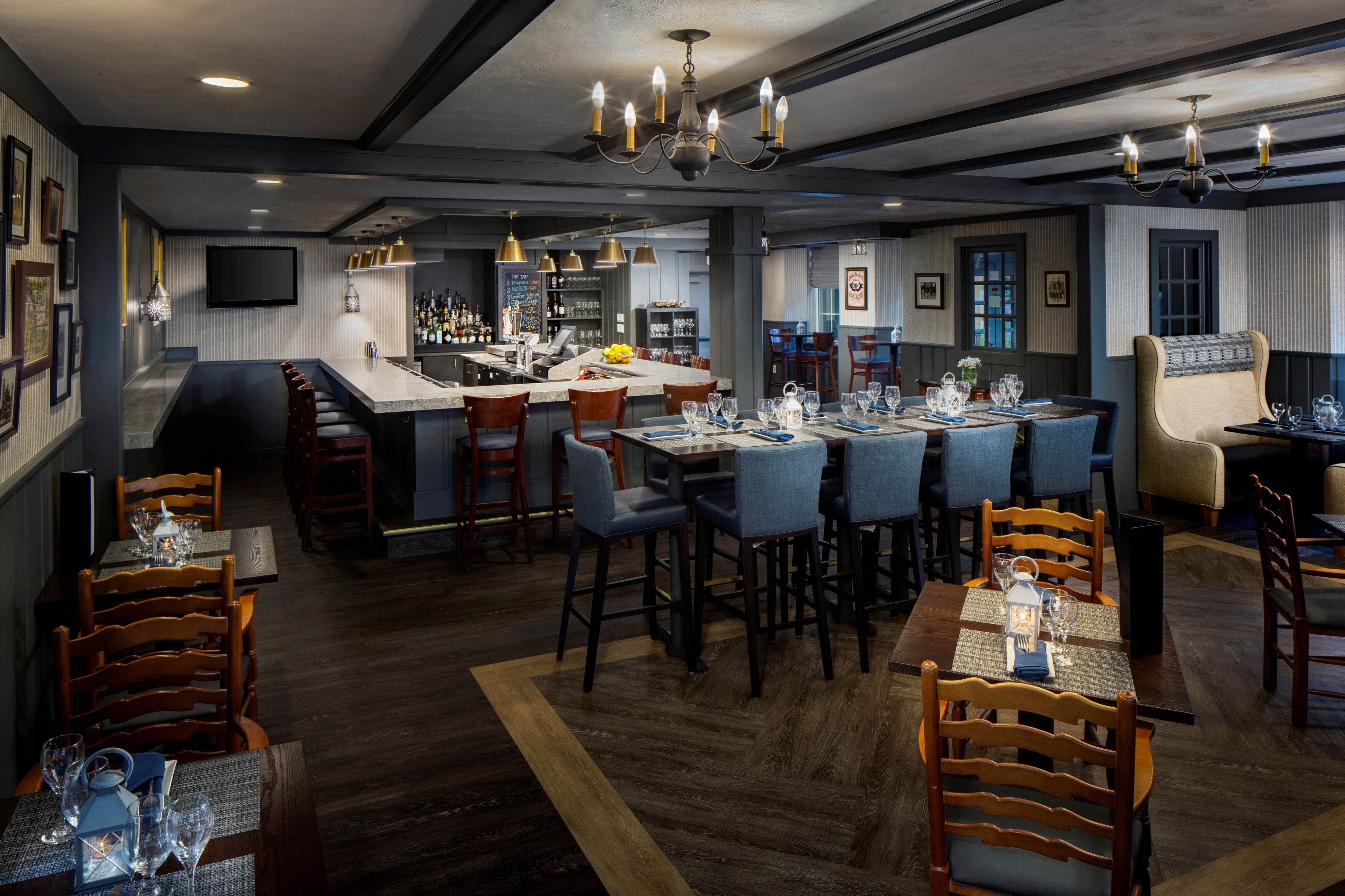 Un espace repas moderne avec un bar, des chaises en bois et un tabouret de bar.