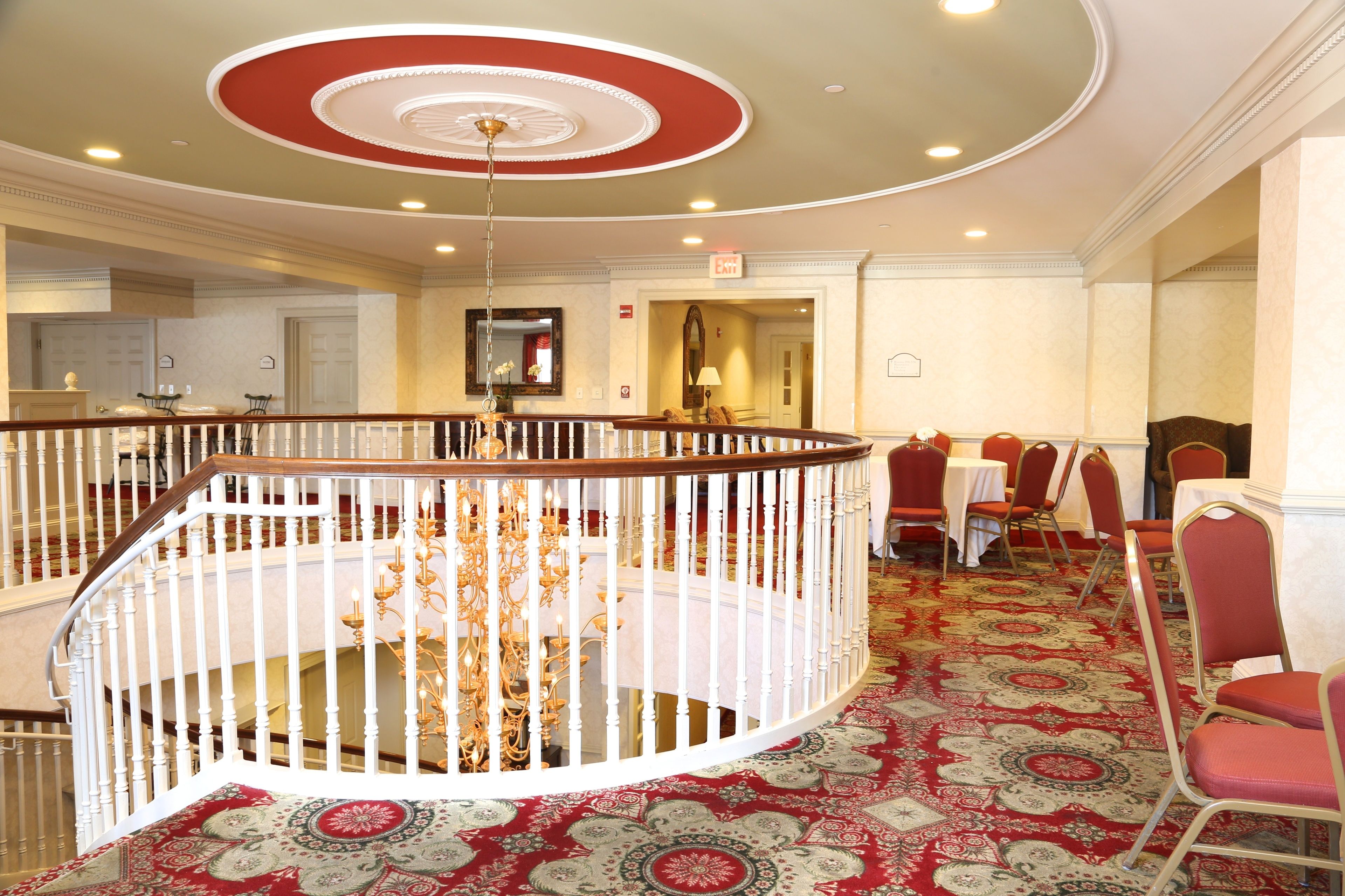 A hotel lobby with a grand staircase, a chandelier, and a patterned carpet.
