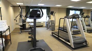 Un gimnasio con cintas de correr, elípticas y equipo de pesas.