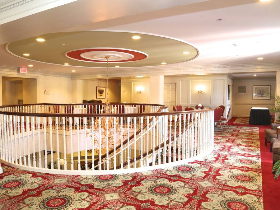 A grand lobby with a circular staircase, a patterned carpet, and a chandelier.