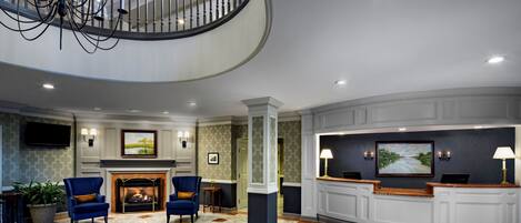 A spacious lobby with a fireplace, seating area, and a reception desk.