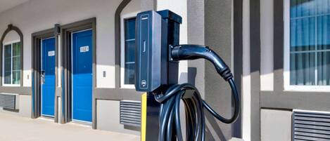 A parking meter with a charging cable attached to a building facade.