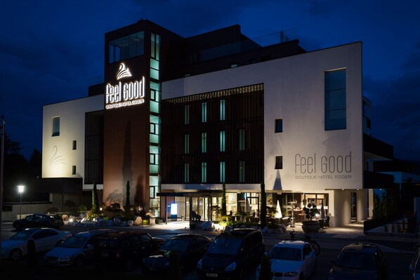 A modern hotel with a prominent 'Feel Good Boutique Hotel Egger' sign. It features a multi-story structure with large windows and a well-lit entrance. - feel good Resort Wörthersee (Krumpendorf am Woerther See)