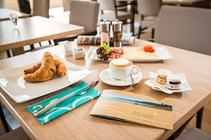 Une table de petit-déjeuner avec des croissants, une tasse de café et des condiments.