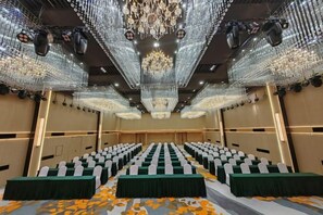 A conference room with rows of tables, a chandelier, and a carpet with a floral pattern. - Sihai Grand Hotel (Anshan)