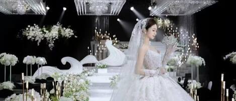 A wedding venue with a white aisle, floral decorations, and hanging chandeliers.