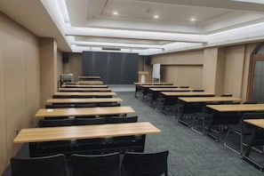 A conference room with rows of tables and chairs, a podium, and a projection screen. - Sihai Grand Hotel (Anshan)