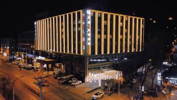 Un hotel de varios pisos con diseño moderno, que destaca por su entrada principal y zona de estacionamiento.