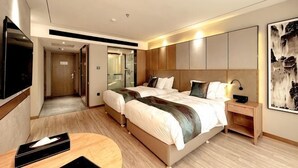 Ein modernes Hotelzimmer mit einem großen Bett, Nachttischen, einem Fernseher und einem Spiegel.