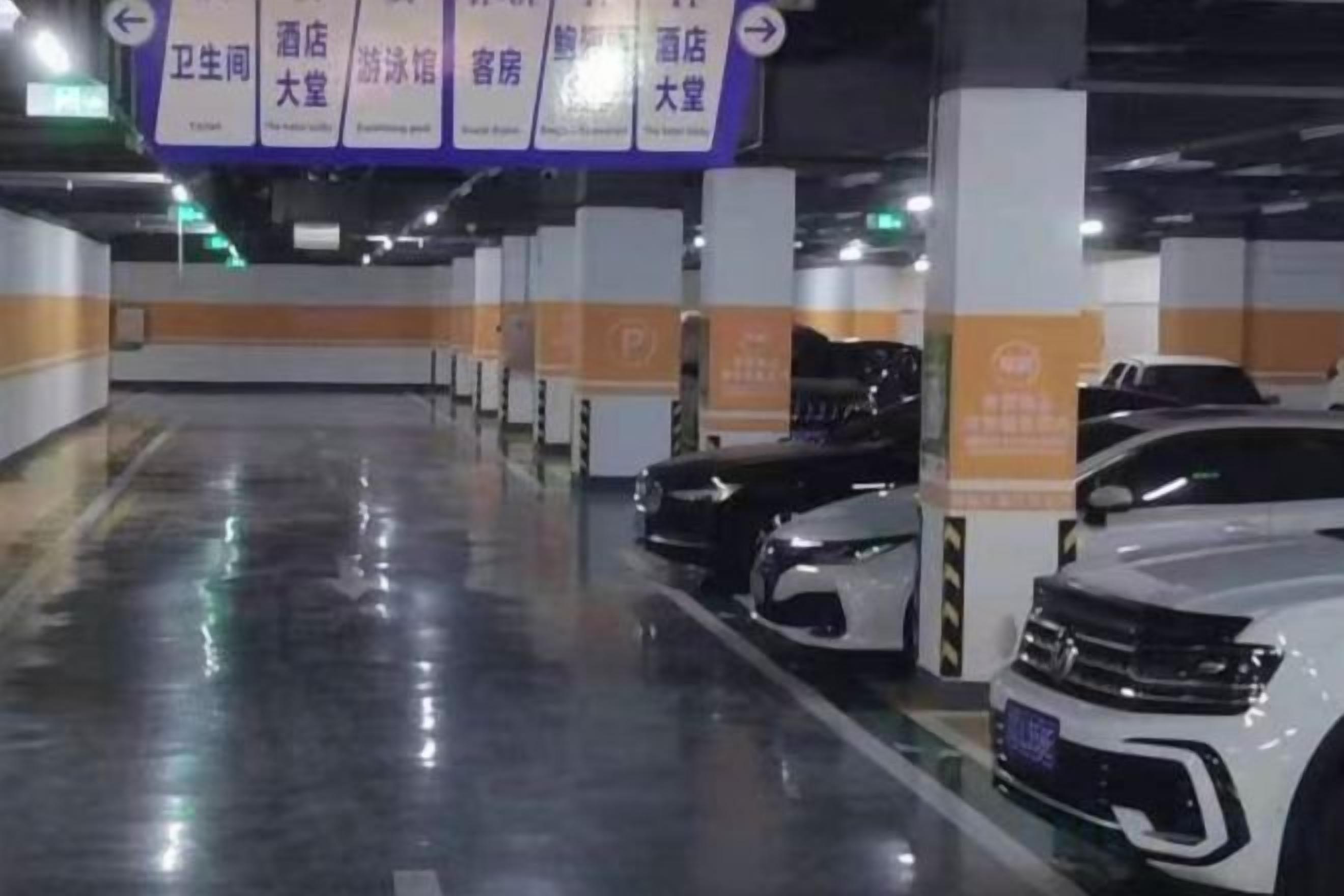 A parking garage with multiple levels, marked parking spaces, and directional signs.