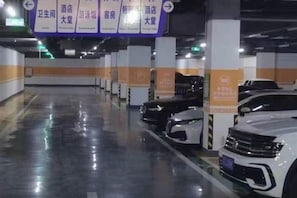 A parking garage with multiple levels, marked parking spaces, and directional signs. - Sihai Grand Hotel (Anshan)