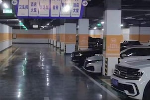 Garagem de estacionamento com vários níveis, vagas demarcadas e placas de sinalização.