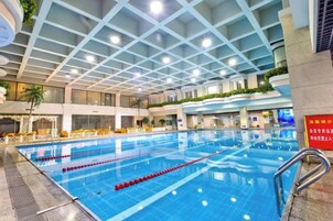 Una piscina interior con divisiones claras para carriles, suelo de baldosas y techo con diseño de cuadrícula.