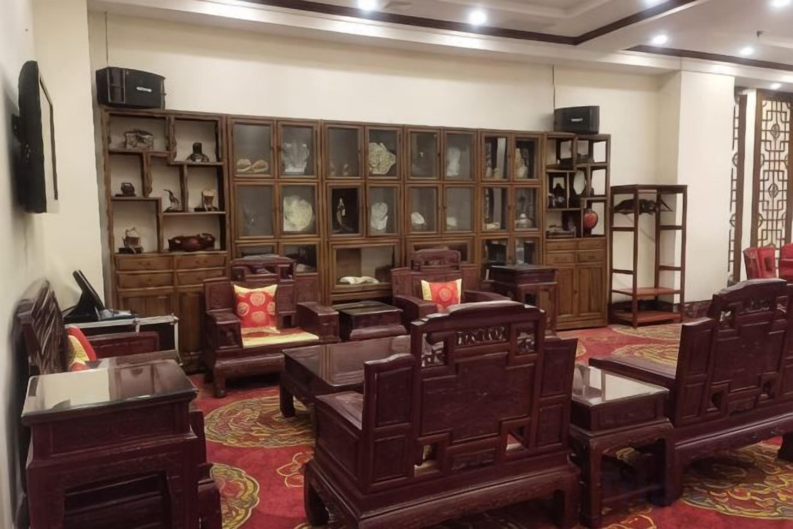 Habitación tradicional con muebles de madera, alfombra roja y una exposición de porcelana.