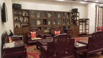 Habitación tradicional con muebles de madera, alfombra roja y una exposición de porcelana.