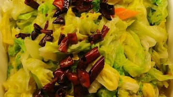 A close-up of a dish with shredded vegetables and red chili peppers.