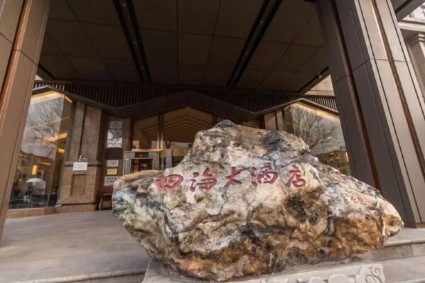 A large rock with Chinese characters in front of a building entrance. - Sihai Grand Hotel (Anshan)