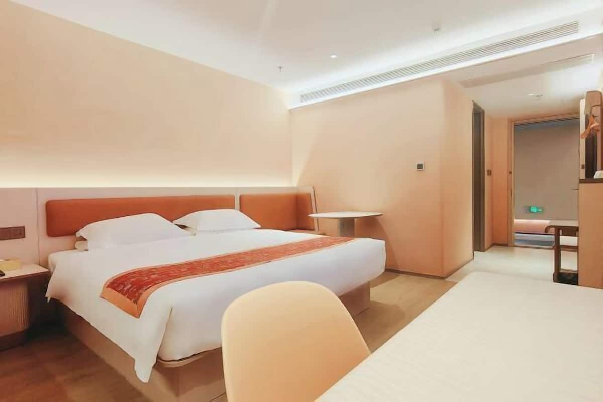 A hotel room with a bed, bedside table, chair, and a small table.