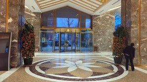 Eine Hotellobby mit Marmorboden, einem großen, kreisförmigen Blumenmuster und einem Glastürrahmen mit einer Drehtür.