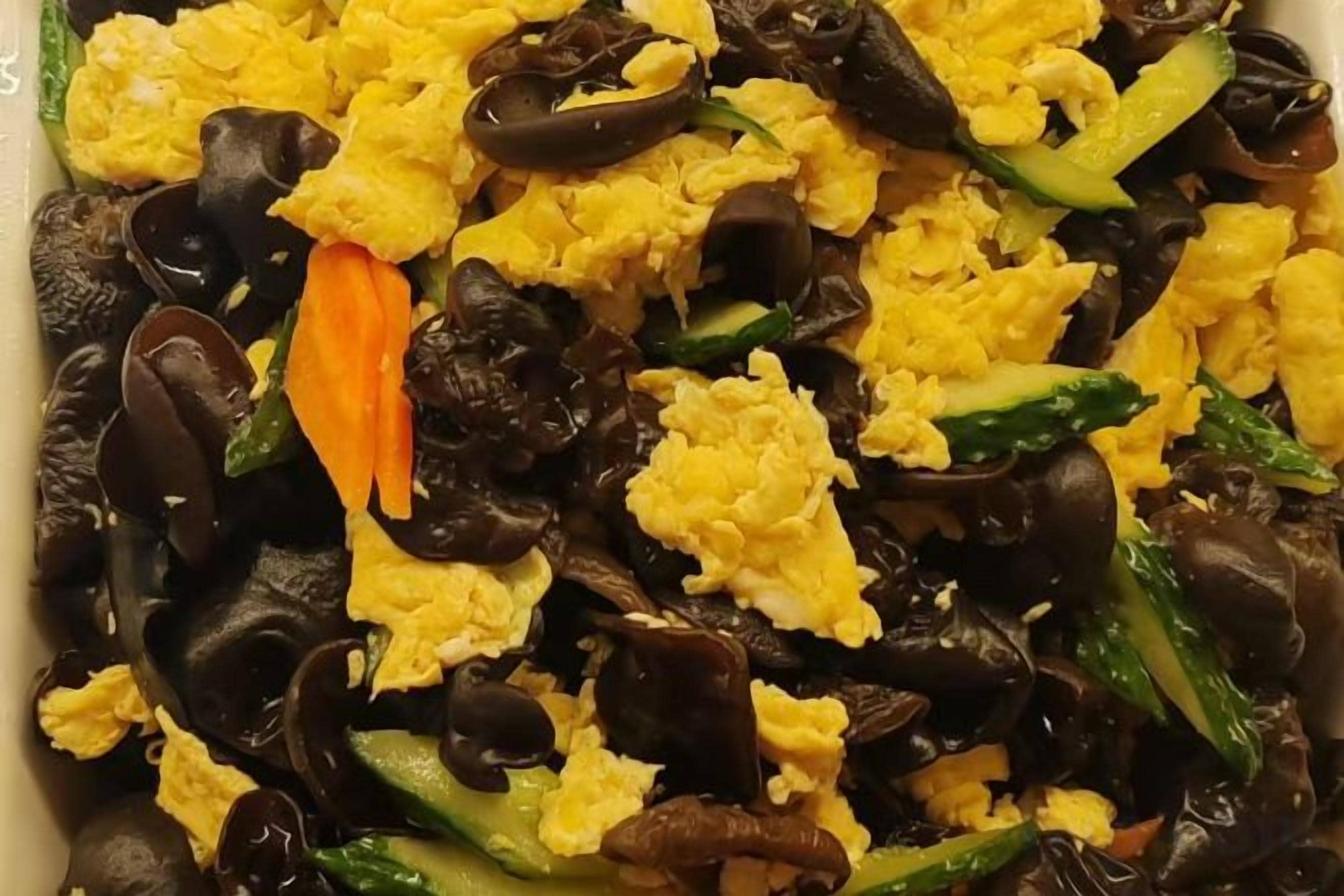 A dish with scrambled eggs, mushrooms, and green vegetables.