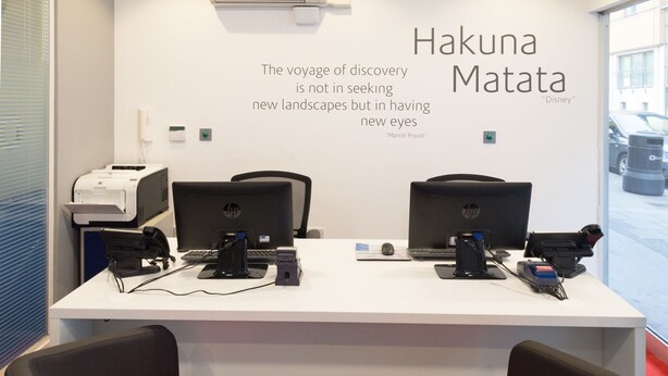 A modern office space with two HP desktop computers, a printer, and office chairs with orange cushions. A quote by Marcel Proust is displayed on the wall. - SACO Holborn - Lamb's Conduit Street (London)