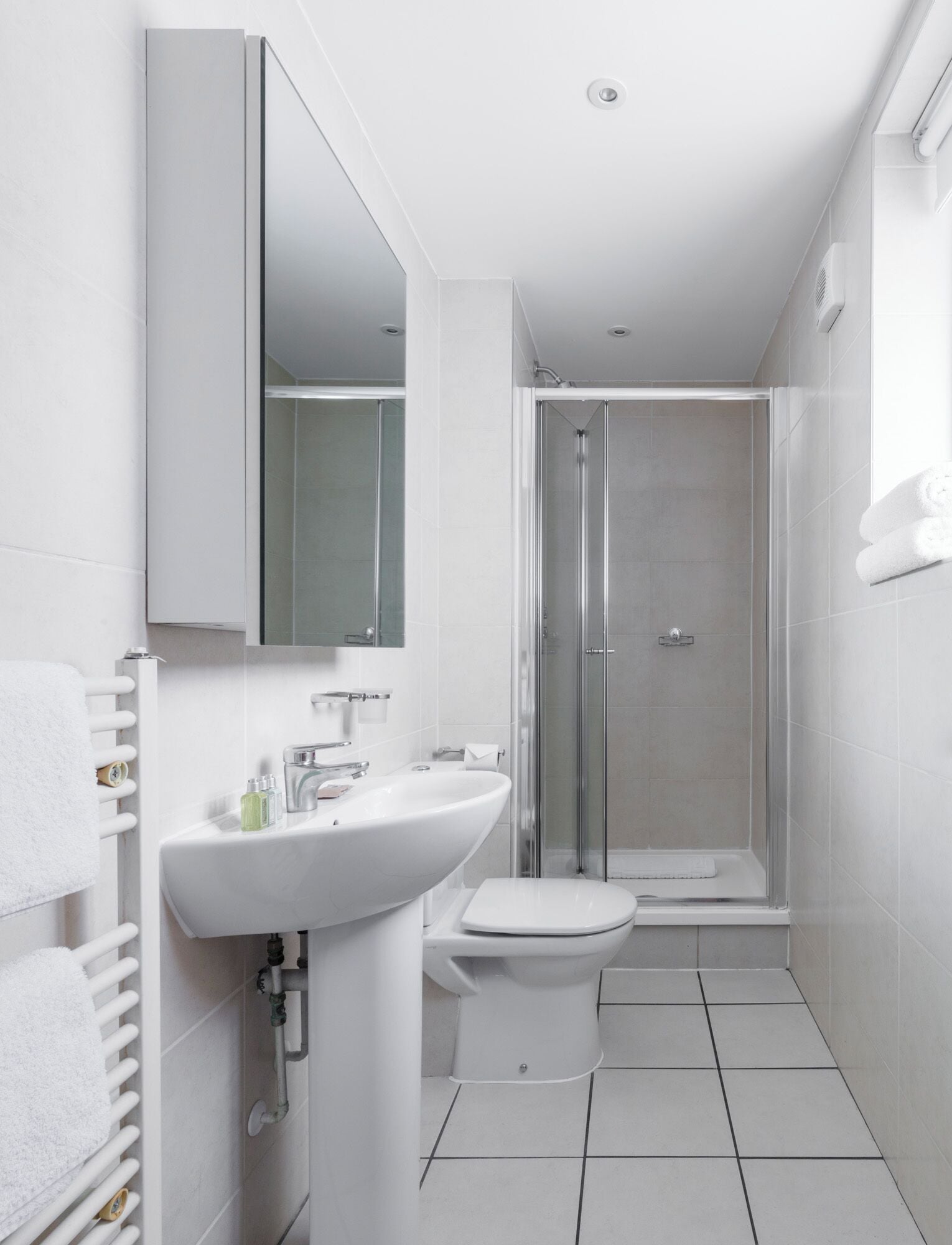 A modern bathroom with a white sink, toilet, and glass-enclosed shower.