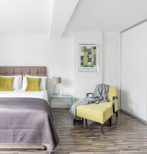 A modern hotel room with a bed, a chair, a nightstand, a lamp, and a framed abstract artwork on the wall. - SACO Holborn - Lamb's Conduit Street (London)