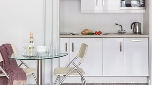 A modern kitchen with white cabinets, a microwave, and a kettle on the countertop. - SACO Holborn - Lamb's Conduit Street (London)