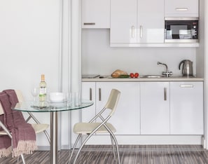 Una cocina moderna con armarios blancos, un microondas y un hervidor sobre la encimera.