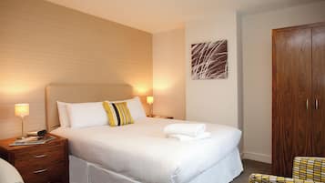 A hotel room with a large bed, two bedside tables, a wooden wardrobe, and a wall-mounted abstract art piece.