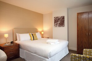 A hotel room with a large bed, two bedside tables, a wooden wardrobe, and a wall-mounted abstract art piece. - SACO Holborn - Lamb's Conduit Street (London)