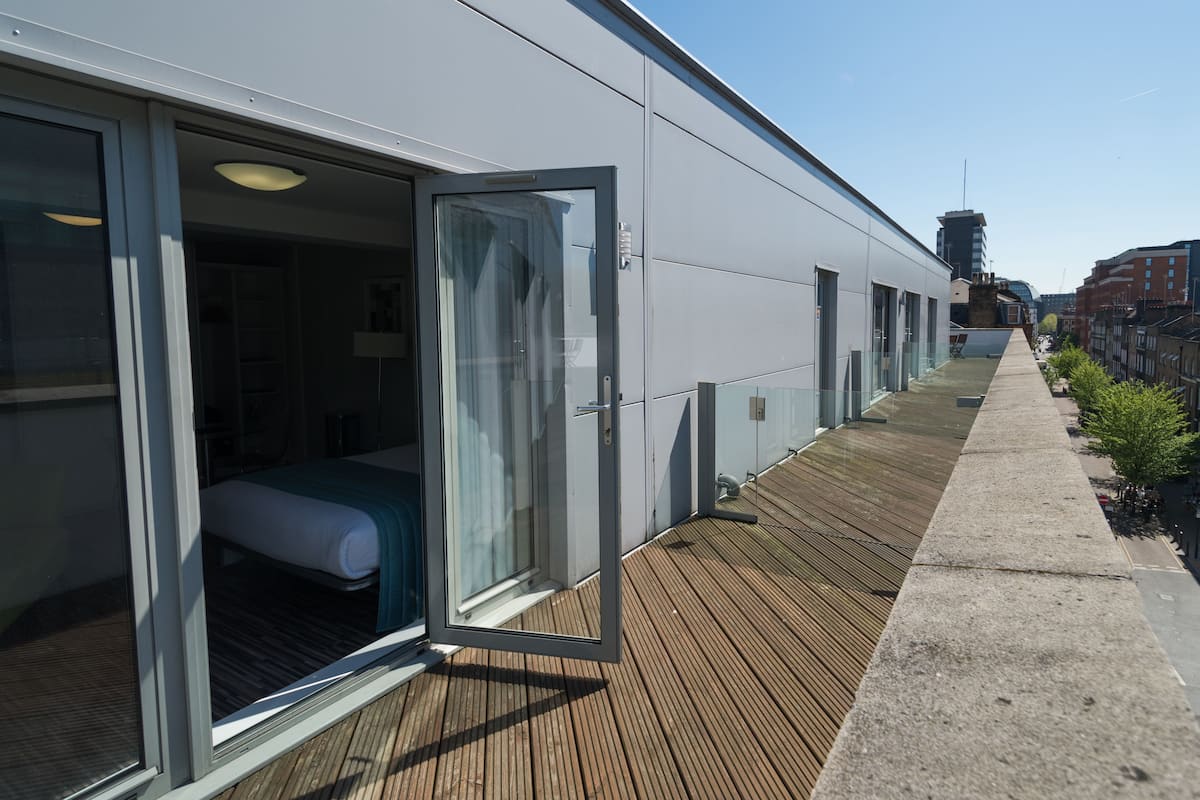 Ein modernes Hotel mit einem gläsernen Raum, einer Holzterrasse und Blick auf die Stadt.
