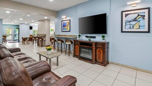 A spacious living area with leather sofas, a dining table, and a flat-screen TV mounted on the wall.