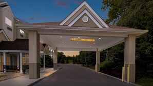 A covered driveway leading to a building with a triangular roof and a sign indicating a clearance of 10 feet.
