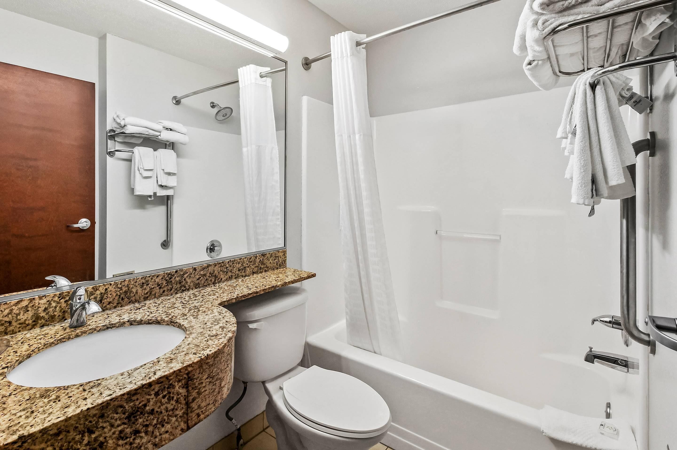 Ein Badezimmer mit Marmorwaschbecken, weißer Toilette und einer begehbaren Dusche mit Glastür.