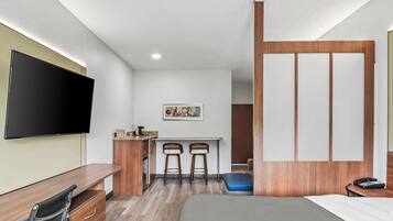 Une chambre d’hôtel moderne, équipée d’un lit, d’un bureau et de deux chaises.
