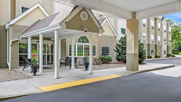 A covered outdoor area with a building entrance, benches, and potted plants.