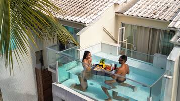 Une maison moderne dotée d’une piscine intérieure à panneaux de verre, d’un toit en tuiles et d’un palmier.