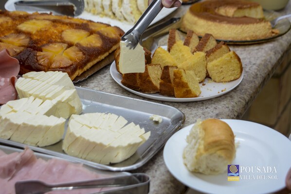 Un buffet proposant une variété de plats, notamment une tarte à l’ananas, du fromage, du pain et des petits pains.
