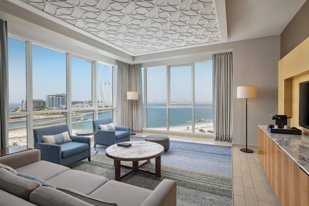 Une chambre d’hôtel moderne dotée d’une grande fenêtre, d’un canapé, d’une table basse et d’un téléviseur.